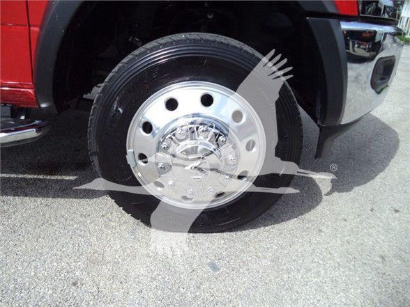 Ram 5500 wheel close-up showing chrome hubcap and tire with body red fender in background.