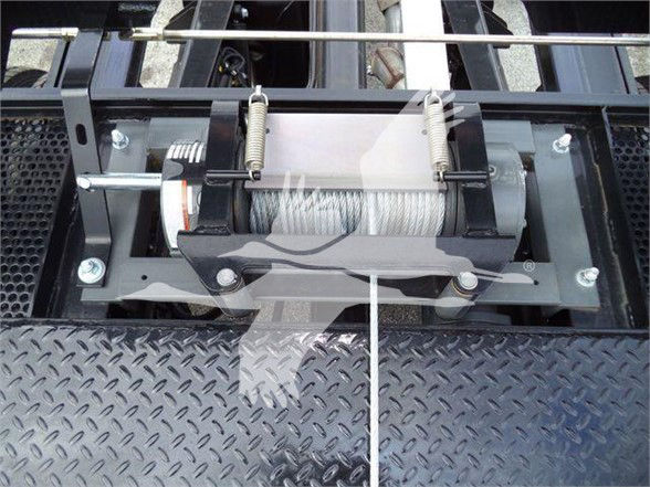Winch system mounted on a steel diamond plate bed with a cable drum, two springs, and metal frame visible.
