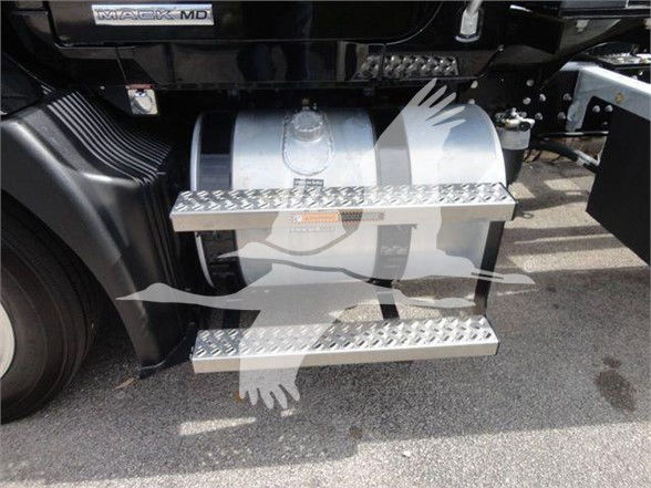 Truck side showing steps and fuel tank with Mack MD6 badge; metal diamond-plate steps under the cab.