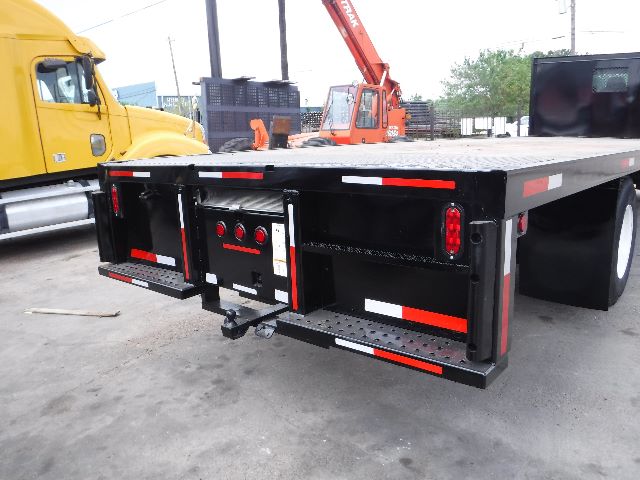 Flatbed trailer rear view on 2018 International 4300 truck setup with reflective strips and bumper lights.