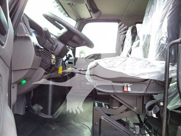 Interior of a 2025 International MV truck cab showing driver seat and steering wheel with protective plastic on seat. Dashboard and pedals visible.