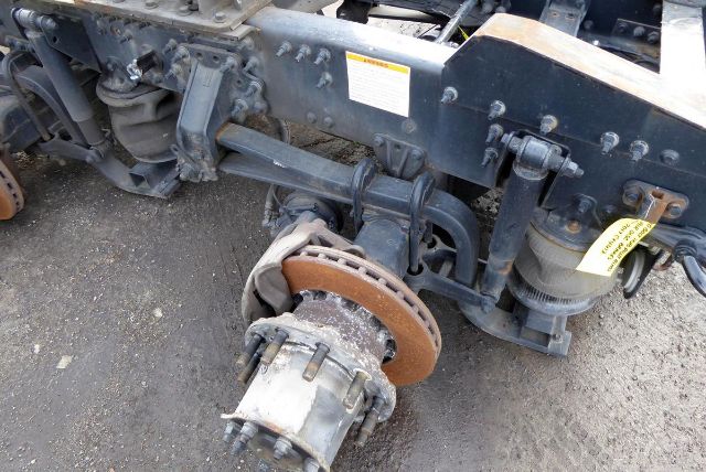 Meritor MT4014X rear axle assembly with brake rotor and hub, visible suspension components, and warning tag.