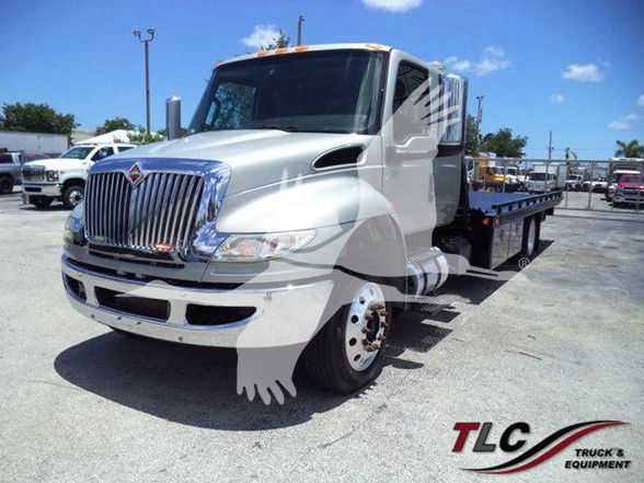 Truck shows a white 2022 International MV tow truck with a flatbed, front grille, and chrome bumper.