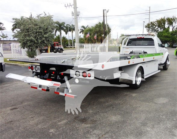 Tow truck showcasing a flatbed with hydraulic lift and rear ramps, from a 2023 Ram 5500 HD SLT listing.