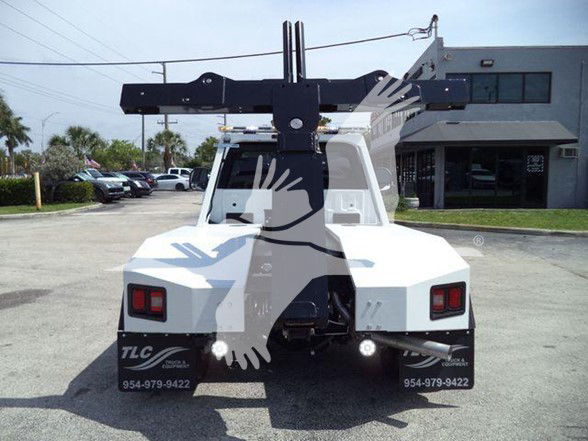Ford F-450 tow truck rear view showing a front-mounted crane and hitch assembly with tail lights and bumper area.