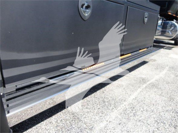 Truck side toolbox with storage drawers and step rail on a new 2022 International MV tow truck showing exterior panels and platform.