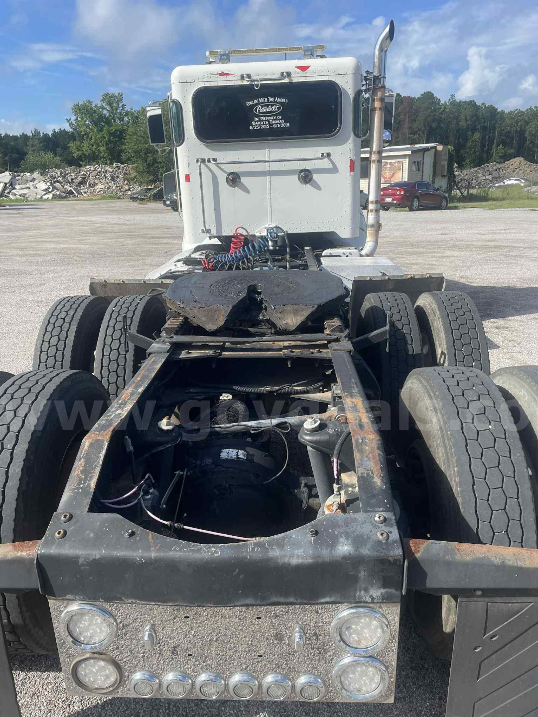 Truck cab and chassis rear view showing Peterbilt 386 cab with dual rear axles, exposed frame rails, air lines, and bumper lights.
