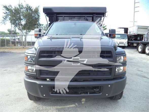 Front view of 2023 Chevrolet Silverado 6500HD refuse truck with large grille and bumper, utility bed in background.