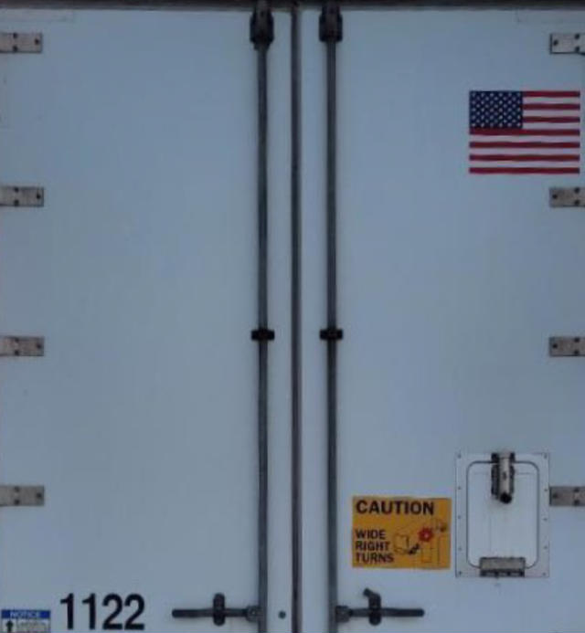 Rear of a Vanguard VXP trailer with double doors, US flag decal, yellow caution sticker, and stock number 1122.