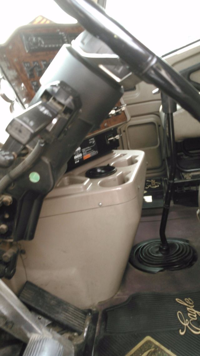 Interior of a 2007 International 9900i showing the steering column, dash, and driver's seat area with a beige center console and cupholders.