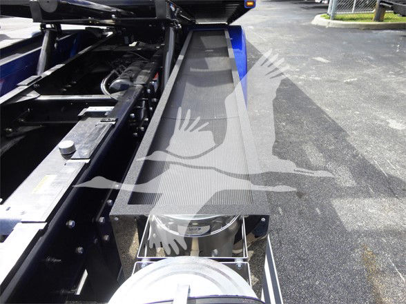 View of a blue 2022 Peterbilt 337 trucks wheel area and side step with metallic steps and components.