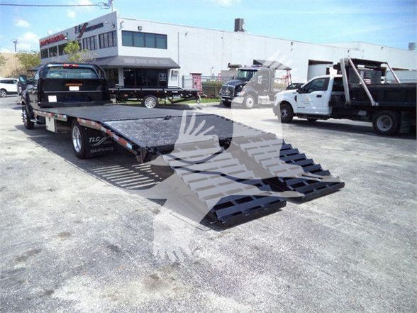 Chevrolet Silverado 6500HD flatbed trailer with ramp system and pickup truck on trailer in lot.