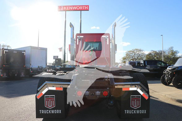 Kenworth W900L tractor rear view with black mud flaps and red cab, stock image at dealership lot.