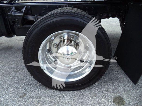 Wheel and tire on truck show chrome hub with steel rim and tire. Visible undercarriage and frame with mud flap.