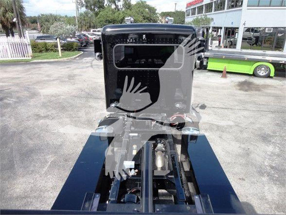 Front view of a 2022 Peterbilt 337 truck cab and chassis in a dealership lot showing the cab interior and front frame rails.
