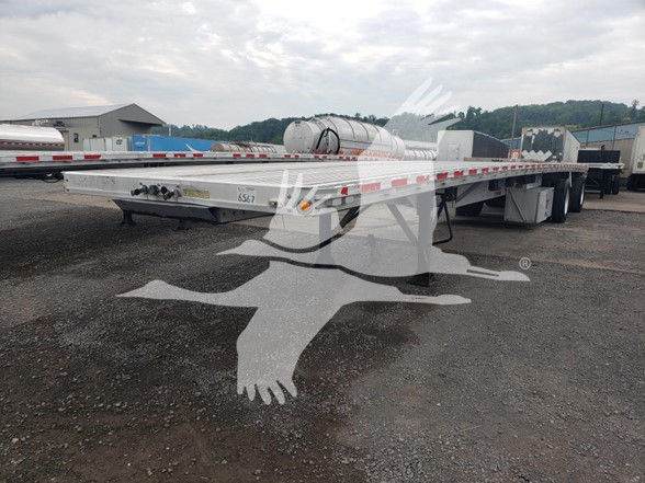 Flatbed trailer with white and red reflective stripe, dual-axle, cylindrical tank behind cab area, 2015 Reitnouer Maxmiser trailer showing stock number 6567.