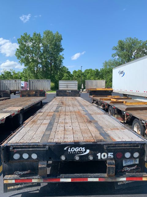 Flatbed trailer with wooden deck showing rear end; visible text includes '105', 'SOO?S', and lights along edges.