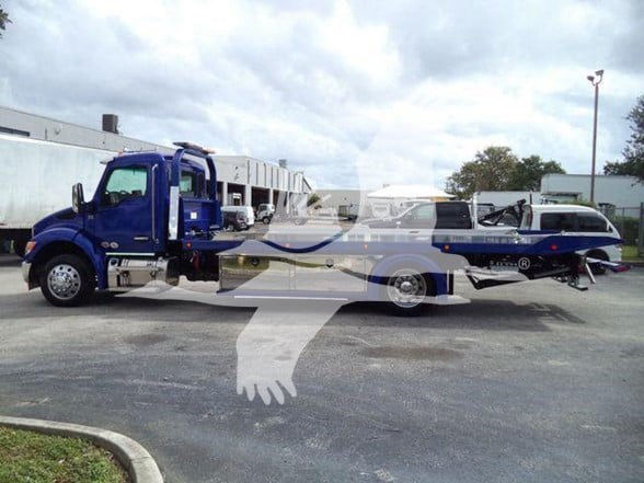 Kenworth T280 tow truck in blue and white livery, flatbed recovery vehicle with wheel lift, shown in parking lot.