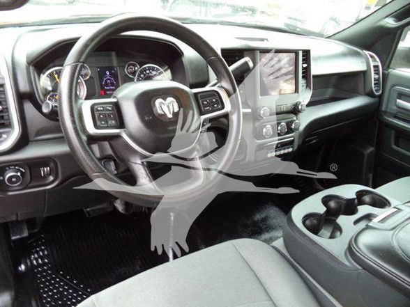 Ram truck interior dashboard and steering wheel with center touchscreen, gear shifter, and cup holders visible.
