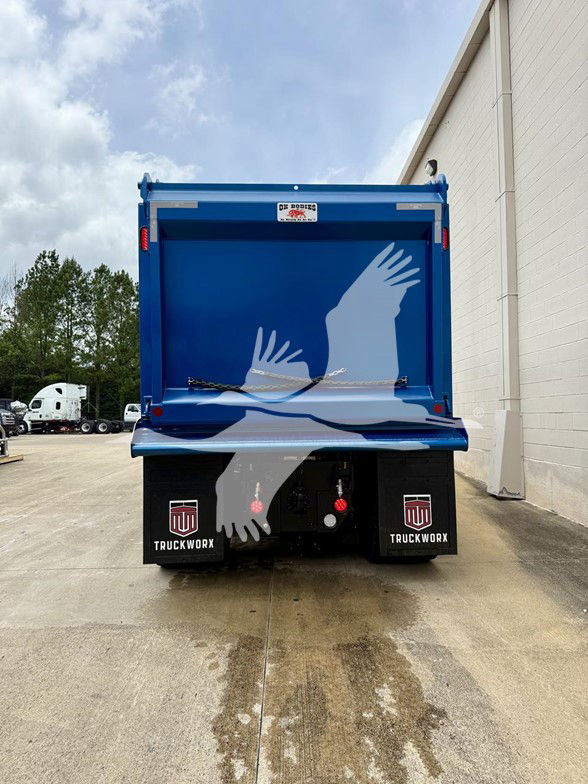 Blue dump truck bed rear view with white graphics of birds; black mud flaps with TruckWorx logos; two red hoses and tailgate area visible.