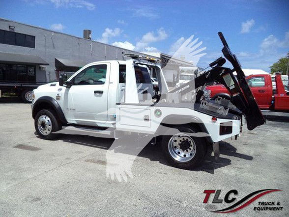 Tow truck setup on a 2023 Ram 4500 SLT with flatbed and hydraulic lift in a dealership lot.