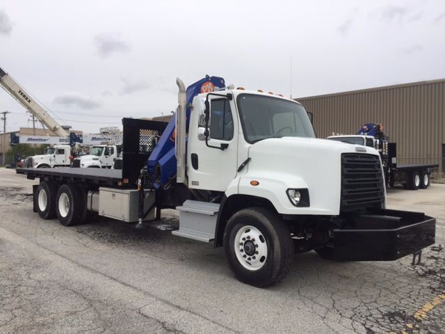 Freightliner 108SD cab mount knuckle boom truck with white cab and blue boom in a parking lot.