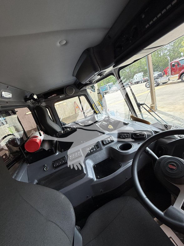 Kenworth L770 cab interior with driver seat, dashboard, steering wheel, and windshield. Visible control panels and seating area.