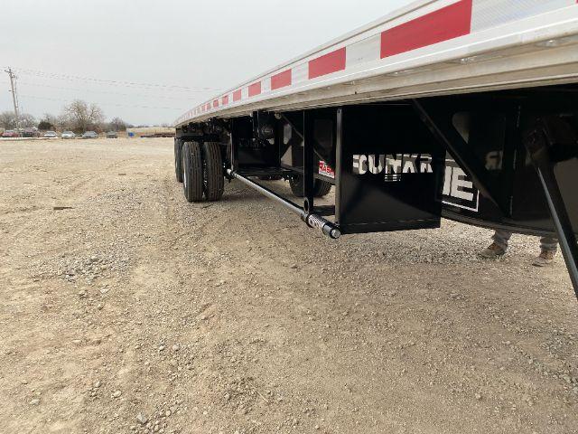 Trailer undercarriage showing dual-axle wheels and frame with support legs and steel brackets.