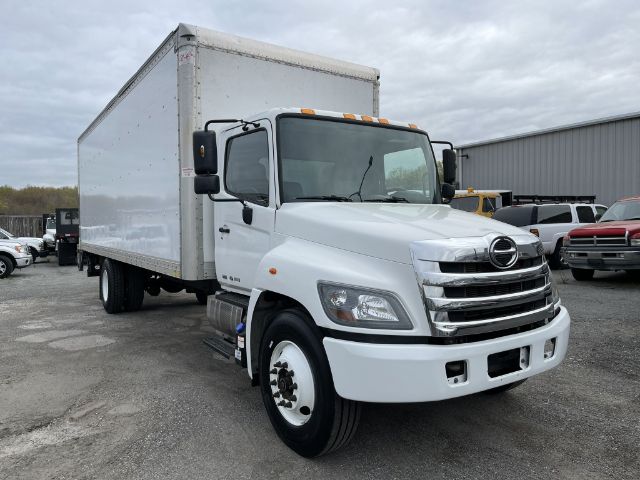 Box truck, white 2017 Hino 268, side view showing cab and large cargo box, front grille with Hino emblem, standard cab mirrors, stock wheels.