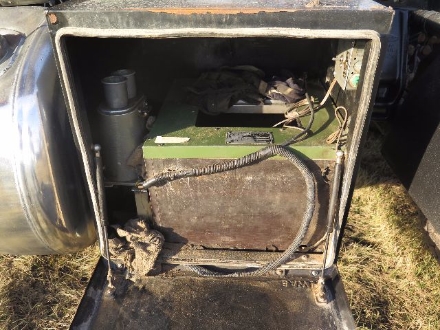 Trunk-style battery/air system compartment of a 2008 Peterbilt 388 showing a green rectangular battery box and various wiring harnesses.