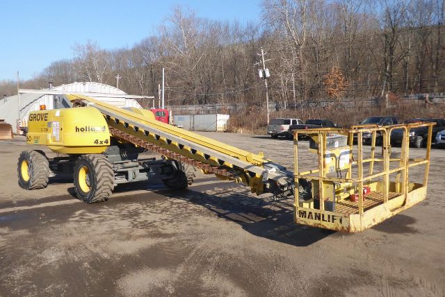 Grove T60 boom lift in a yard showing extended yellow boom and basket at the end.