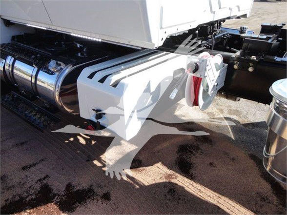 Truck rear section showing heavy-duty hitch assembly and side fuel tank with chrome cylindrical tank; white chassis with black frame and electrical components visible.