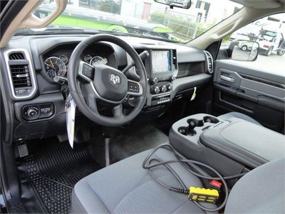 Ram 4500 HD interior showing steering wheel with RAM logo, touchscreen display, center console, and front seats with a cable and tester on the passenger seat.