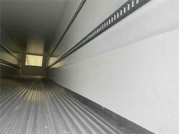 Interior of a CIMC Cool Globe reefer van trailer showing insulated walls, ribbed side rails, and corrugated metal floor with a small window at the far end.