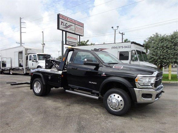 2024 Ram 4500 SLT tow truck in black with flatbed, front grille visible, Ram badge, chrome bumpers, large dual rear wheels, dealership lot in background.