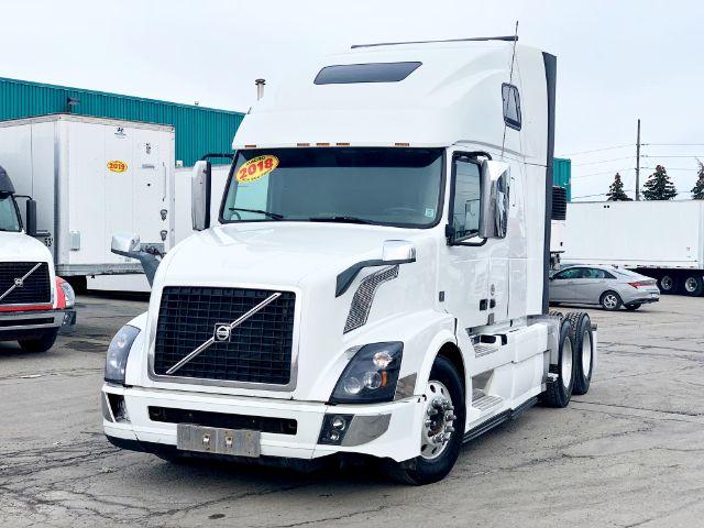 Volvo VNL 670 truck in white, front-left view, 2018 model year sticker on windshield, sleeper cab, dual rear axles.