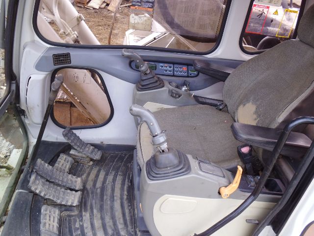 Operator cab of a Link Belt 330LX excavator showing joysticks, pedals, and control panel along with seat; interior wear visible on seat cushion.