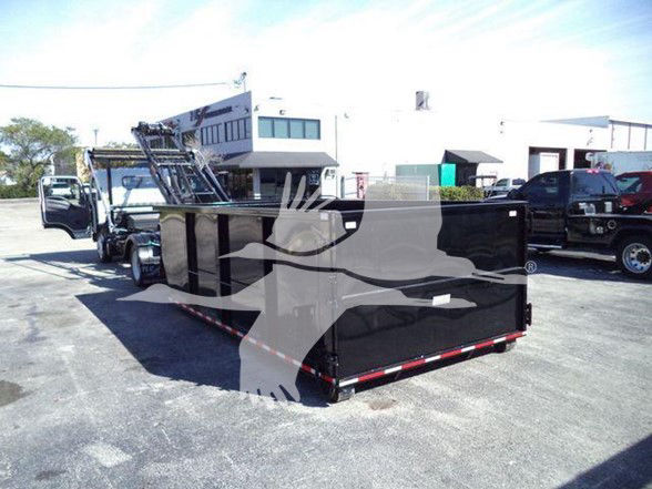 Isuzu NRR dump truck with a large black flatbed/container in a lot; front cab visible, rear side open tailgate shows equipment trailer.
