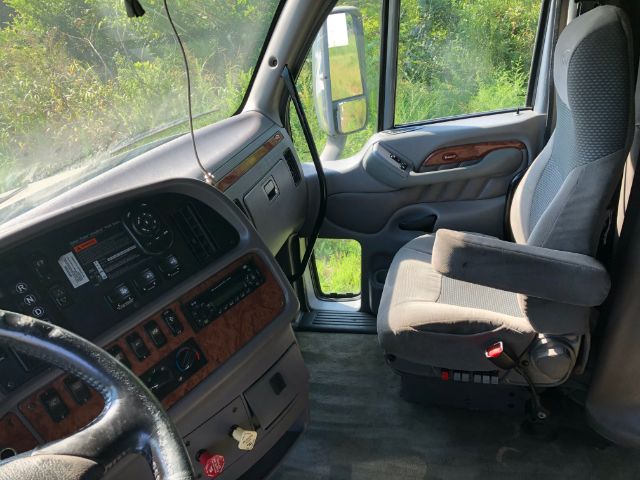 Interior cab view of a 2011 Peterbilt 387 showing steering wheel, dashboard with wood grain accents, driver seat, and doorway.