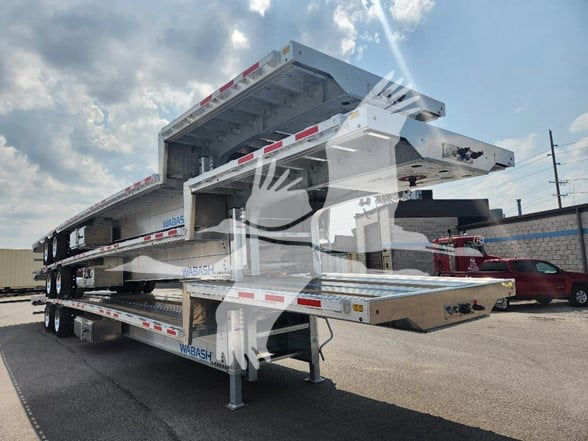 Wabash drop deck trailer stacked with multiple levels, white and silver with red and white reflective markings, parked in lot.