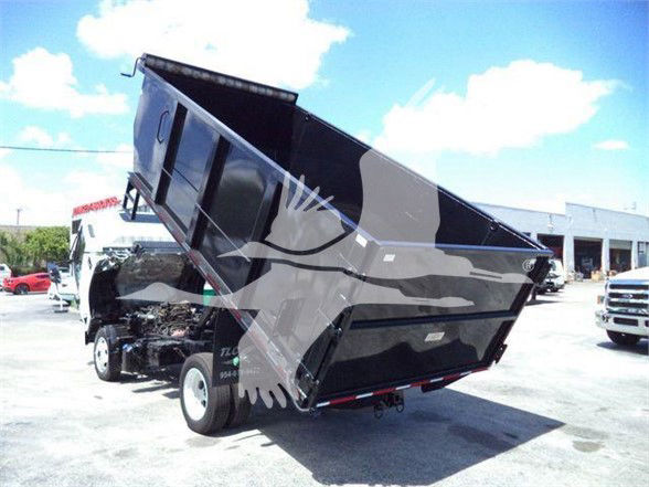 Isuzu NRR dump truck tilted with raised dump bed showing chassis and front wheel.