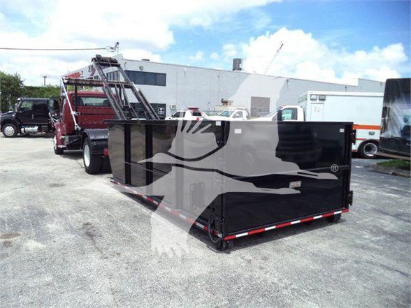 Flatbed dump-like trailer attached to a Freightliner BUSINESS CLASS M2 106 in a used truck lot; black trailer with white silhouette watermark obstructing some details.
