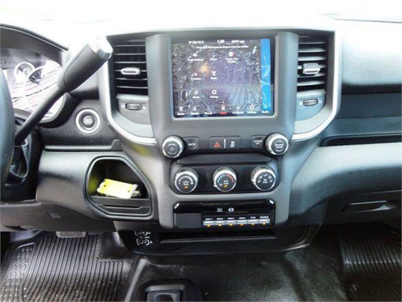 Ram 4500 dashboard with large touchscreen display, circular climate controls, and vent slots. Center console shows storage pocket with card, below are control buttons and small digital display.