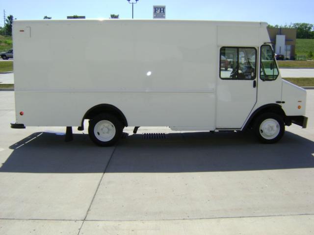 White Freightliner MT45 step van side view showing cargo box, cab with windows, and front wheel with step.