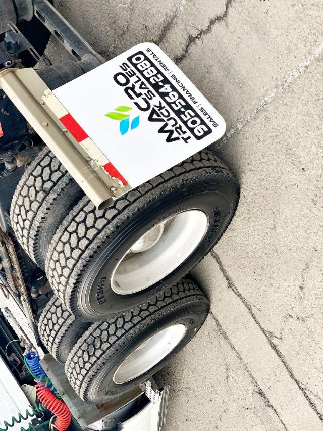 Volvo truck wheel area with dual rear tires and a white sign reading VOLVO TRUCKS S...