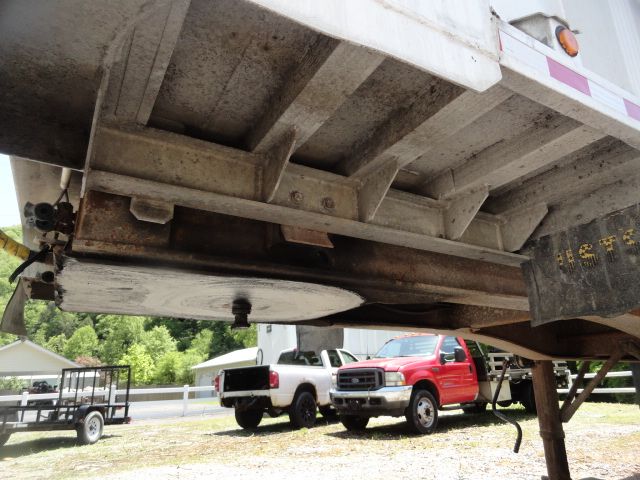 Underneath a 1998 USTS 32ft trailer showing frame and support beams, rusted metal components, and a portion of the trailer’s underside with a plate and structure.