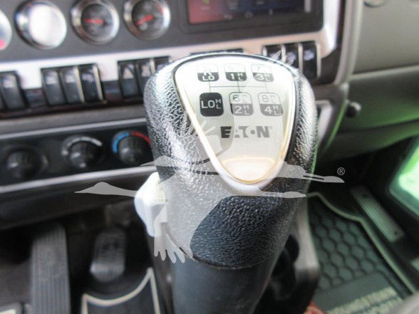 Kenworth W900L interior with gear shifter showing Eaton 10? transmission control labels on top, dashboard with gauges and vents.