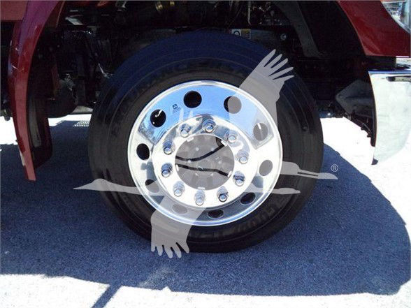 Wheel and front fender of a Kenworth tractor with polished steel wheel and lug nuts visible; watermark overlay obscures some details.