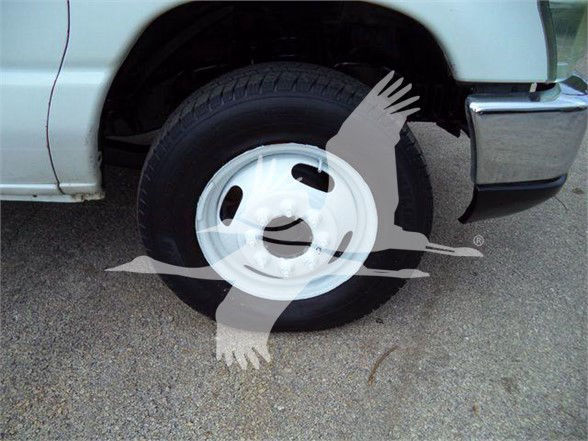 Ford E450 wheel and front fender showing front tire and white steel wheel, partial step side and chrome bumper.