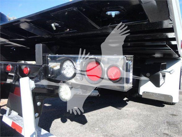 Tow truck rear showing lighting and hitch assembly with circular red reflectors and gauge panel.